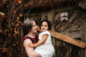 Mom and toddler hugging in front of old barn door in the Pacific Northwest 