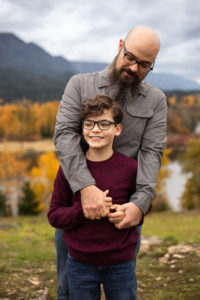 Dad and son hugging on cliff near the columbia river gorge. 