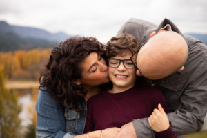 mom and dad kissing son on cheeks in the gorge 