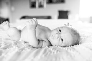 Black and white image of a newborn laying on bed in blog about what to wear for newborn photos. 
