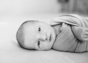 Black and white image of newborn baby in swaddle for blog about what to wear for newborn photos. 
