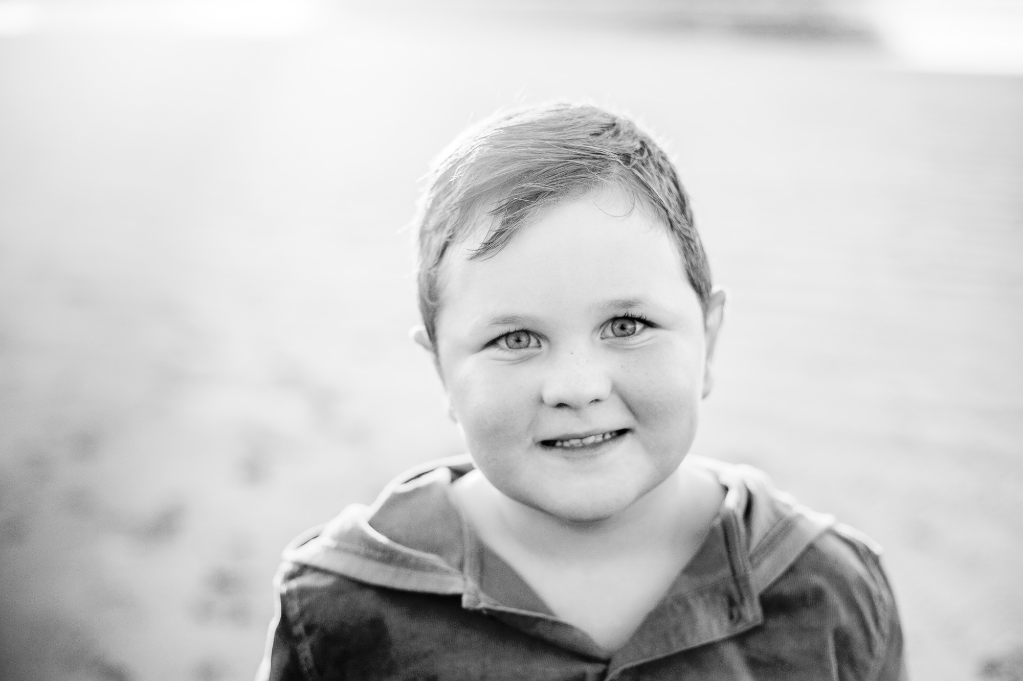 Black and white image of young boy at beach.