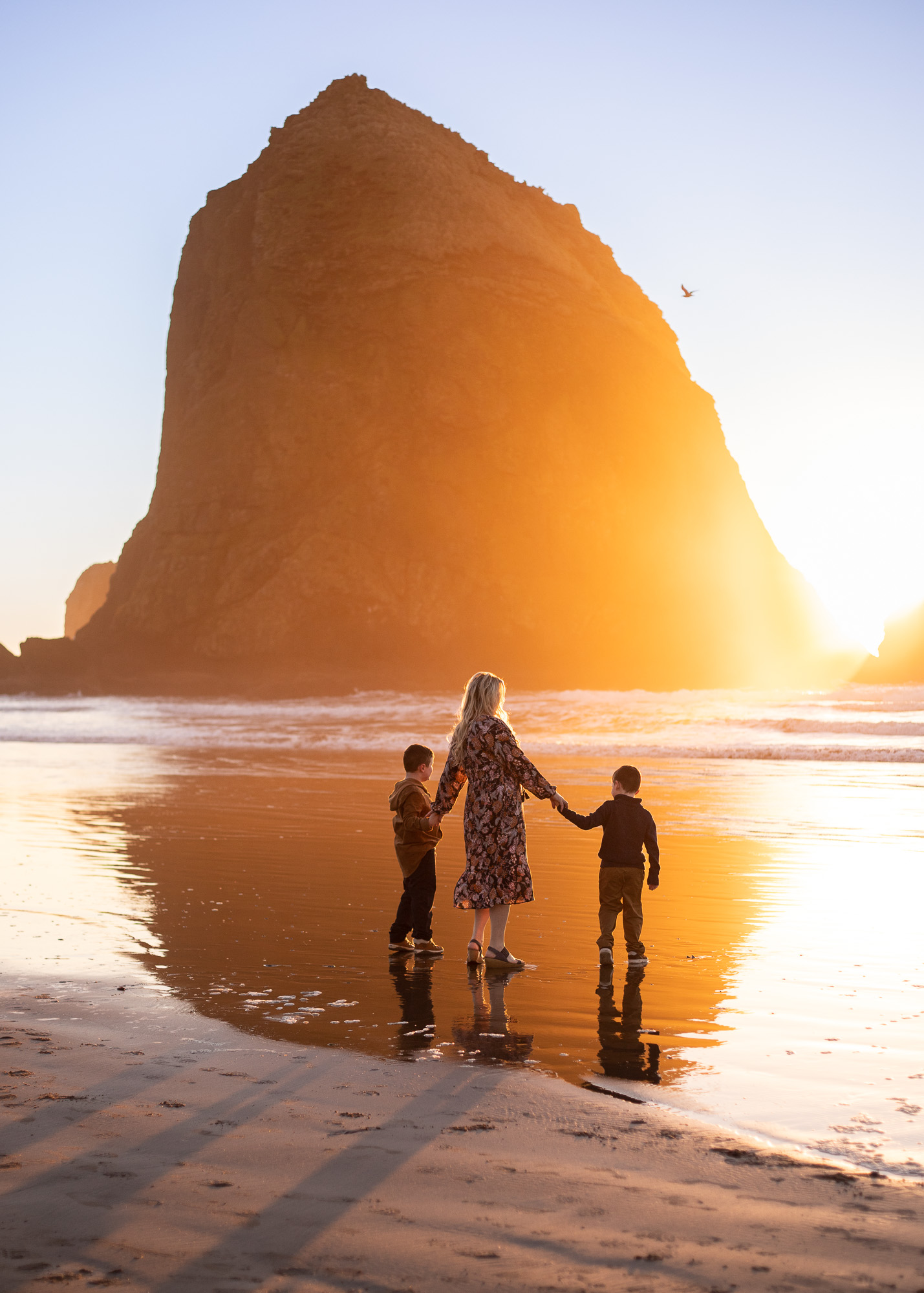 Cannon Beach Photographer captures mom with sons in front of Haystack Rock at sunset. 