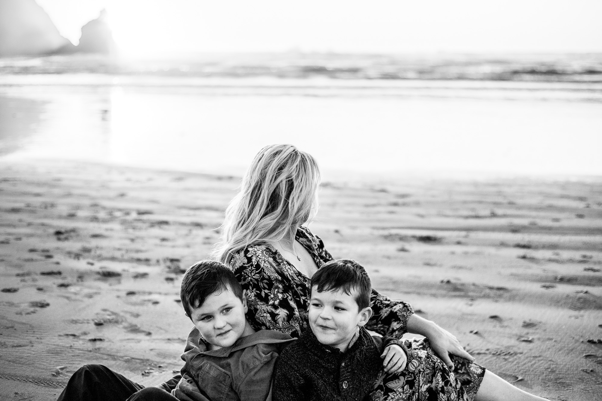Black and white image of mom and boys at beach.
