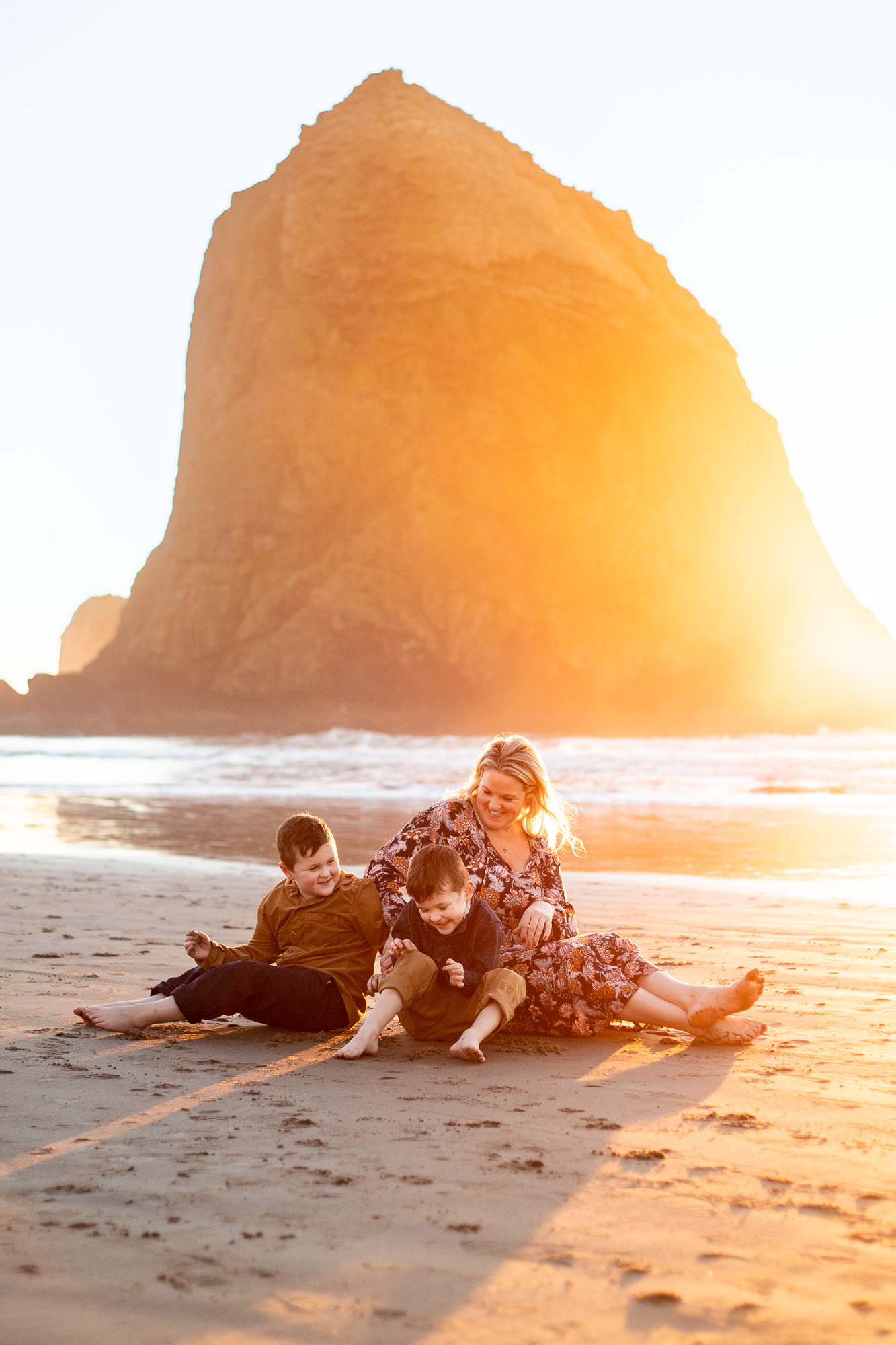 Family sitting on beach in front of Haystack Rock, Oregon.
