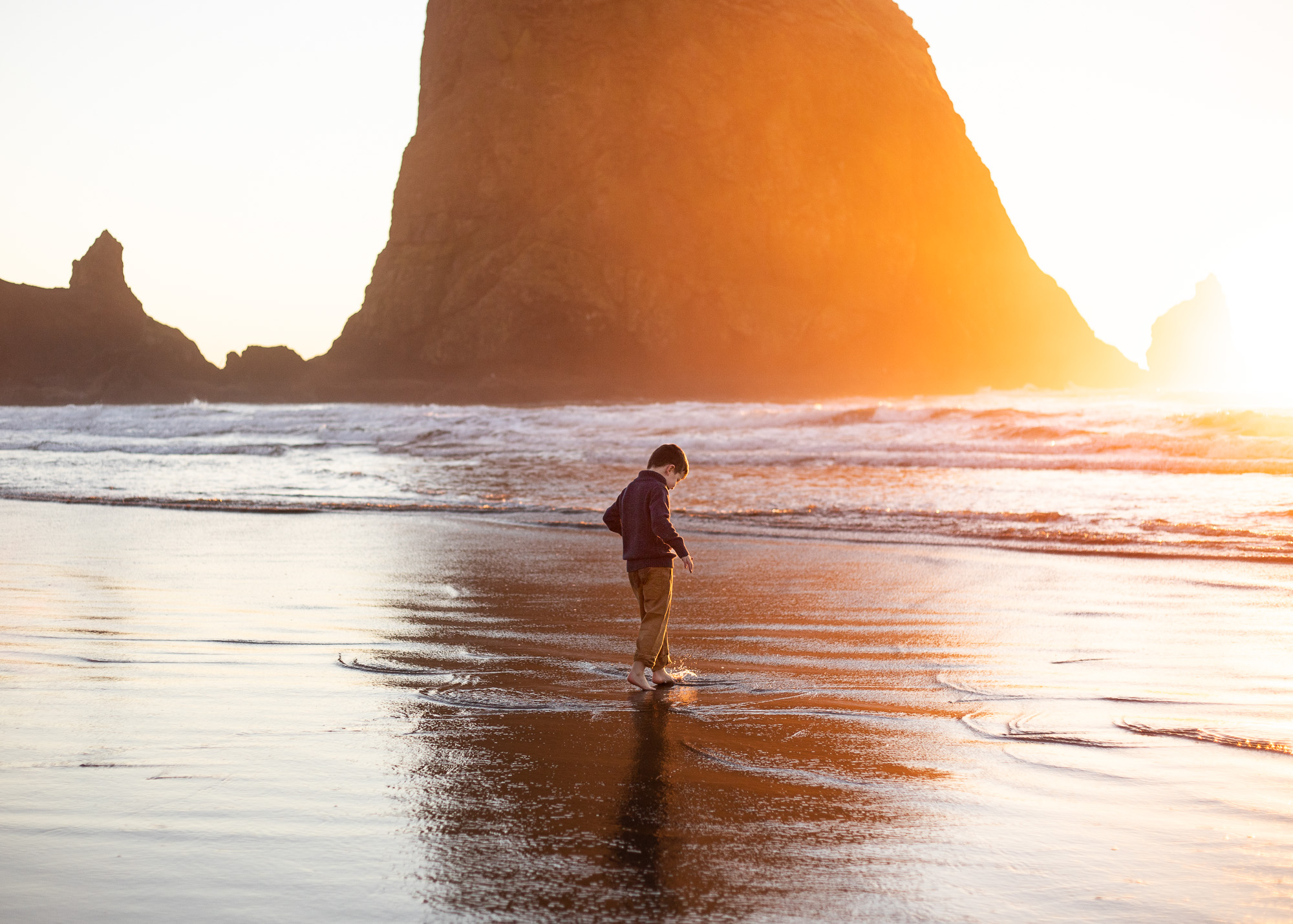 Young boyo playing on beach during sunset with Cannon Beach Photographer