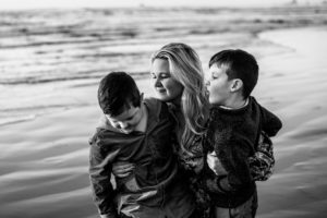 Black and white image of mother with two sons on beach at Oregon Coast. 
