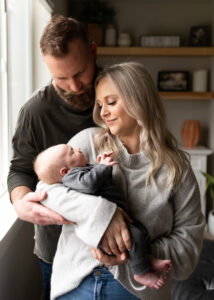 Couple holding newborn son in natural light in blog about what to wear for newborn photos. 
