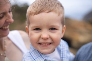 Oregon Coast Photographer| Little boy smiling at the camera while having his photo taken on the beach.
