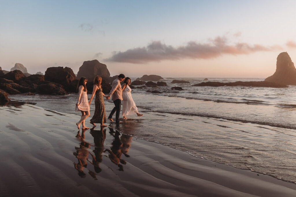 Family walking through shallow water together on the beach.