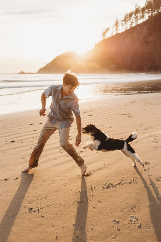 Boy playing with the family dog on the beach during a sunset photo session.