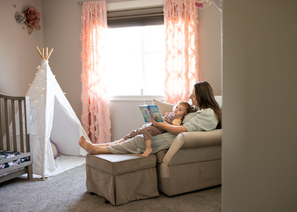Mom sitting on chair reading to toddler in pink bedroom | Valentines Day Ideas 