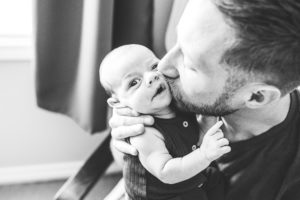 black and white image of dad kissing newborn baby