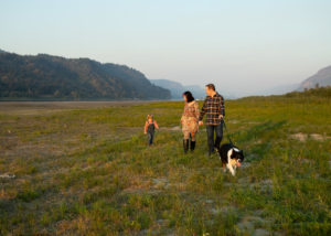 Family of three with dog exploring Rooster Rock State park. 