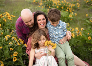 Family of four laughing in yellow wildflowers near Hood River, Oregon.