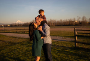 A family of three and pregnant mom kissing in front of Mt Hood near portland, oregon. 