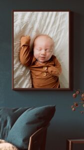 Newborn photo in a large vertical frame on the teal wall.