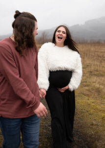 Couple laughing and holding hands for a rainy Portland maternity photo shoot. 