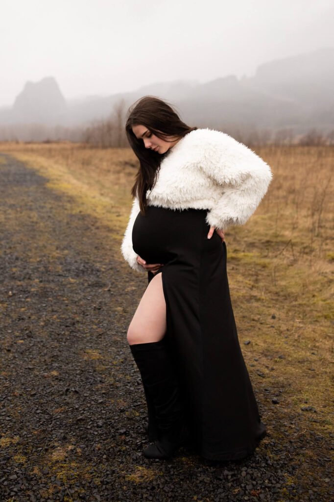 Pregnant woman holding her belly in the Columbia River gorge, wearing a black dress | Maternity dresses for photoshoot 