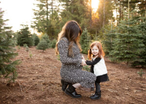Toddler holding pregnant moms tummy at a tree farm in Oregon state. Portland prenatal massage
