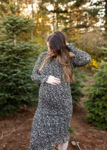 Pregnant woman holding tummy at tree farm in Portland. | Portland prenatal massage