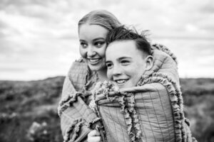 siblings hugging in gray blanket during winding day in the Columbia River Gorge.