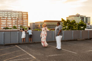 Family of four looking out at sunset at the top of a parking garage while parents dance near Portland, Or, area. 