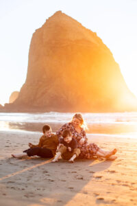 Mother and two sons sitting on cannon beach at sunset. Things to do in the Oregon Coast. 