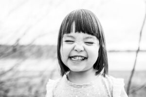 Black and white of little girl smiling with her eyes closed. 