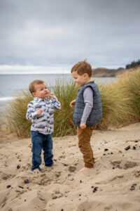 Young brothers are playing on the beach at Pacific City, Oregon. Things to do in Pacific City Oregon for Families. 