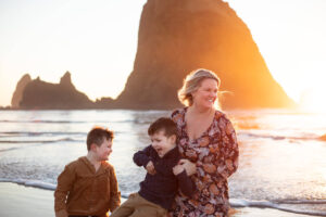 Mom and sons are running in front of Haystack Rock at Cannon Beach, Oregon—things to do in the Oregon Coast. 