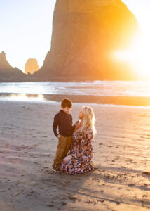 Mother and son are looking at one another in a beautiful sunset in front of Haystack Rock in Cannon Beach, Oregon—things to do in the Oregon Coast. 