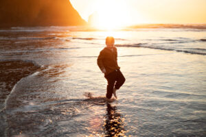 Young boy standing on the shore at sunset in Cannon Beach, Oregon. 