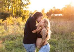 Expecting parents kissing in the field. Portland Prenatal Yoga