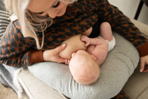Mother breastfeeding newborn in chair | Portland Lactation Consultants