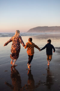 Mother and young sons running in the sunset at Cannon Beach Oregon.