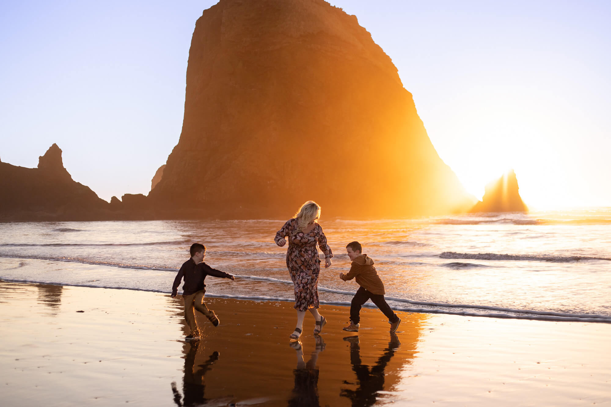 Mom with two young sons running in Cannon Beach Sunset.