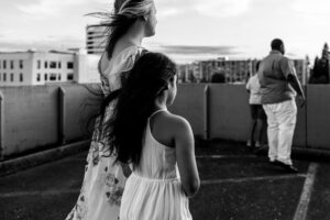 Black and white image of a mom and daughter atop a parking garage in Vancouver, Wa watching the sunset. 