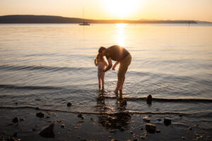 Dad and daughter standing on the shore at sunset at West Beach Resort.