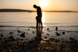 Dad and daughter standing on the shore at sunset on Orcas Island
