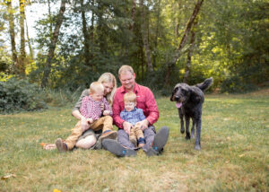 A family of four sitting at a park in the grass near Portland, Oregon with their dog. 