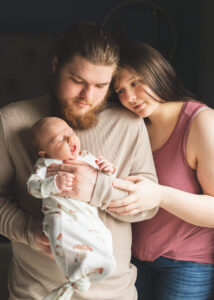 New parents holding newborn son while he yawns. 