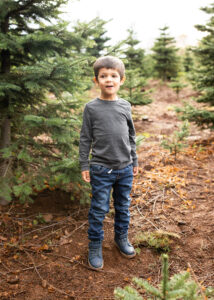 A young boy standing in a tree farm for family photo shoot near Portland, Oregon. 