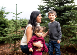 A mother with her two young kids laughing at a tree farm near Portland, Oregon.