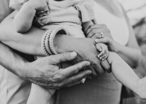Black and white image of family holding hands at family photo shoot. 