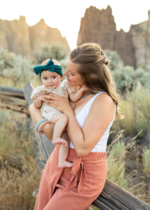Mother with a baby girl sitting on the fence at Smith Rock State Park, Oregon.