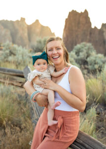 Mother with baby girl sitting on fence at Smith Rock State Park, Oregon.