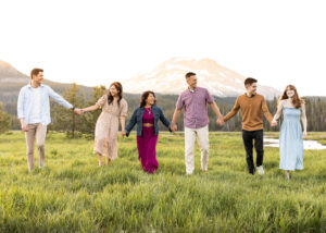 Family of six walking in a meadow in front of South Sister in Bend, Oregon.