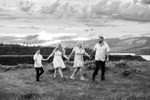 Black and white photo of family holding hands walking in wildflower field in Hood River, Oregon. 