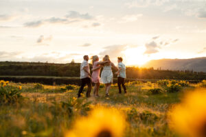 Family of four looking out at the sunset in Hood River, Oregon in spring wildflowers. 